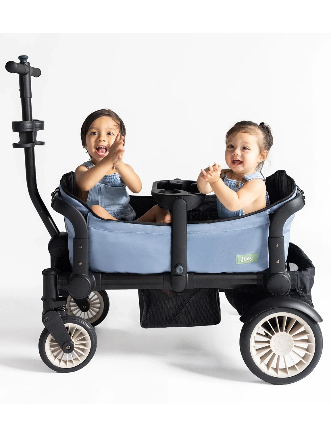 Two children sitting on opposite ends of a Joey wagon, between the handy snack tray.