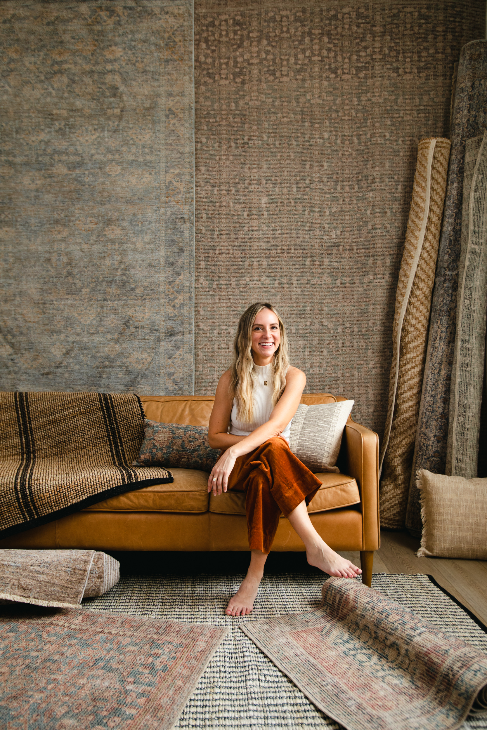 Angela Rose sitting on sofa surrounded by rugs