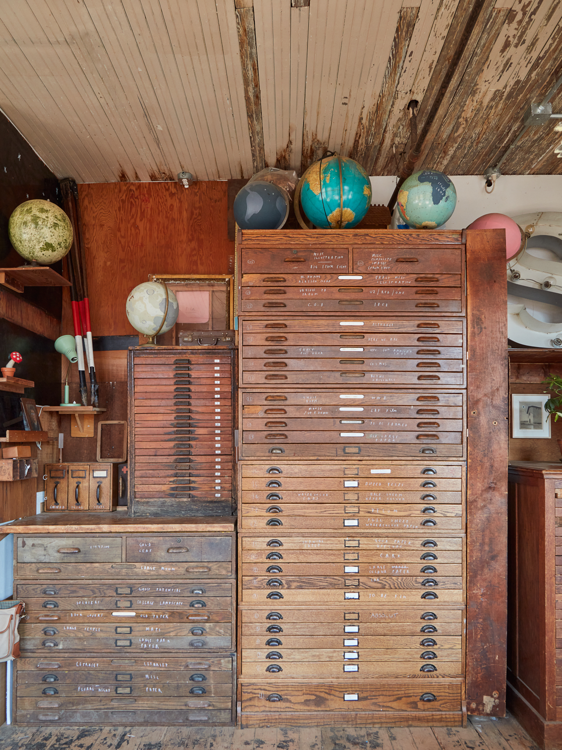 Several tall and staggered wooden drawers with a cluster of globes sitting atop.