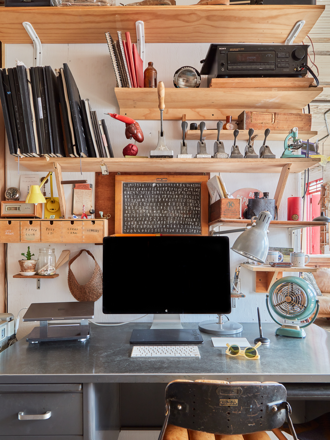 Metal office desk below several rows of wooden shelves.