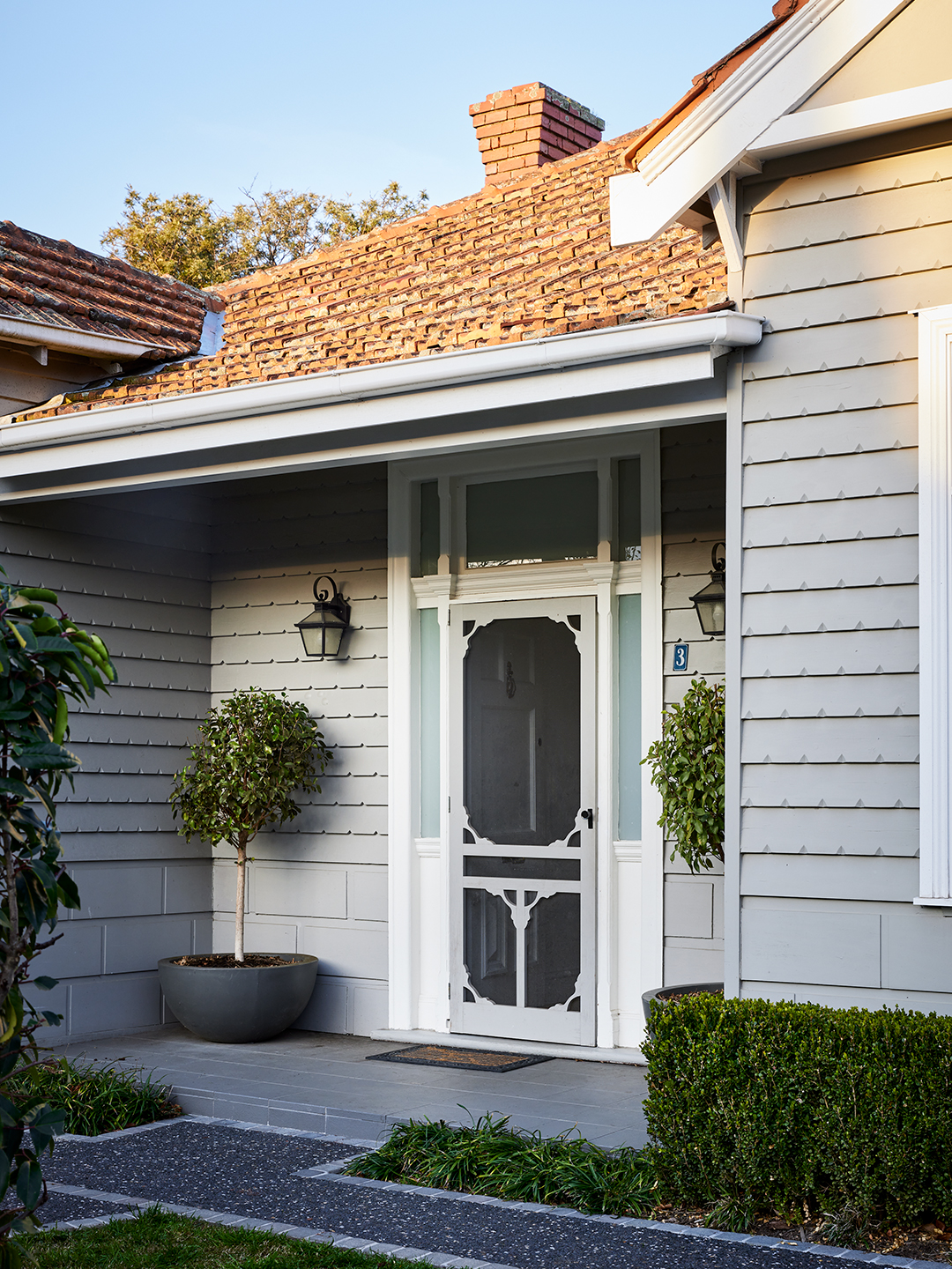 Gray painted exterior of Edwardian home with trimmed hedges and bushes in front