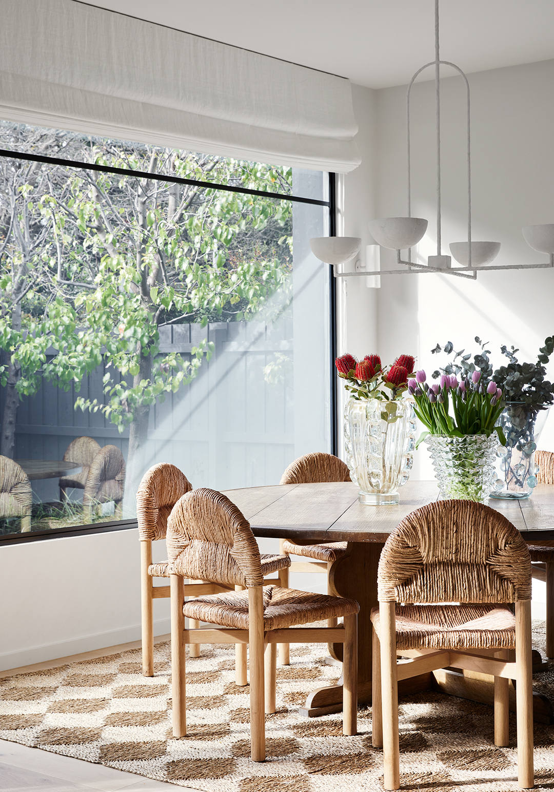 dining room with diamond jute rug and woven dining chairs 