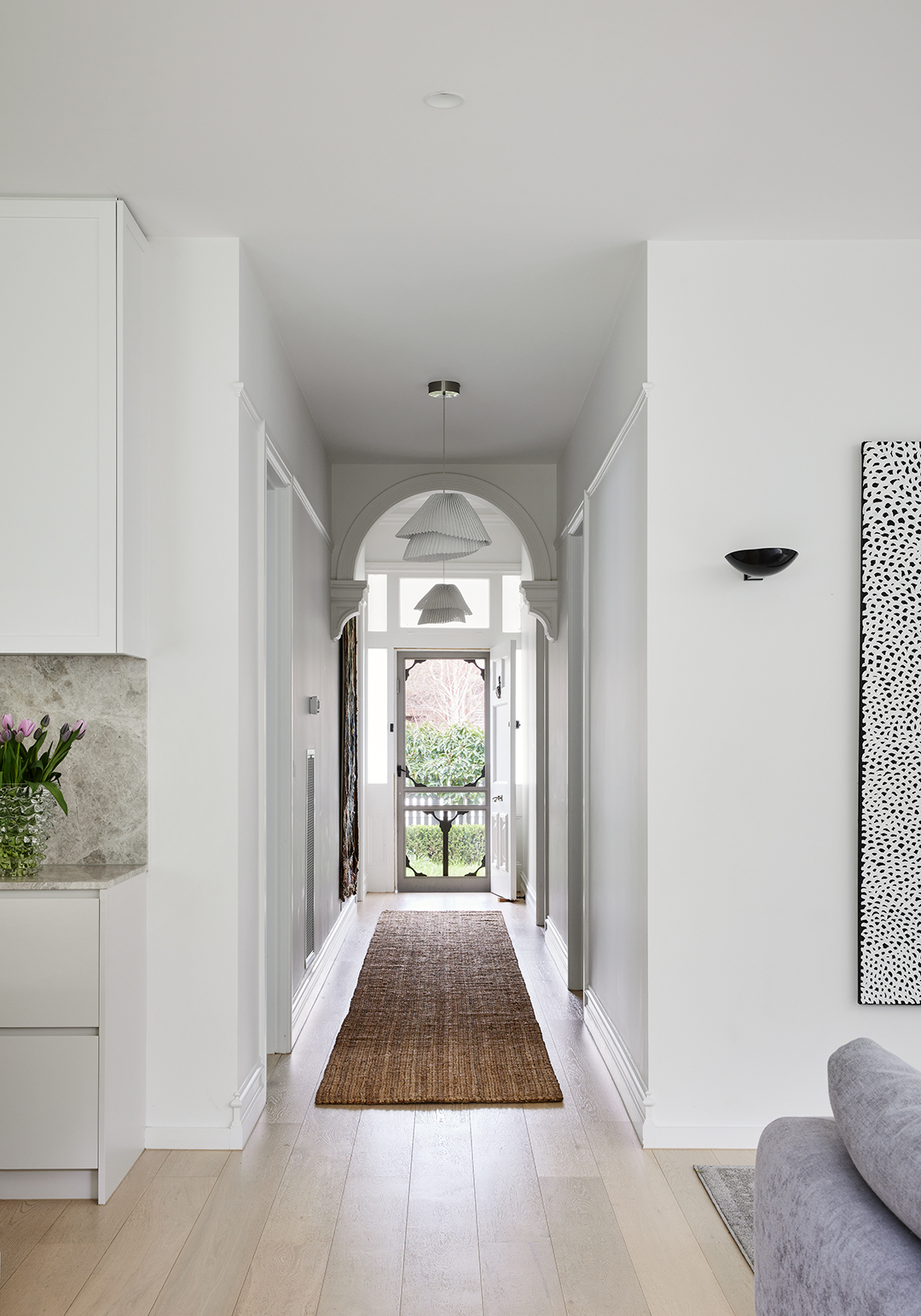 hallway shot looking from kitchen to front door with two pendant light fixtures and Edwardian moldings