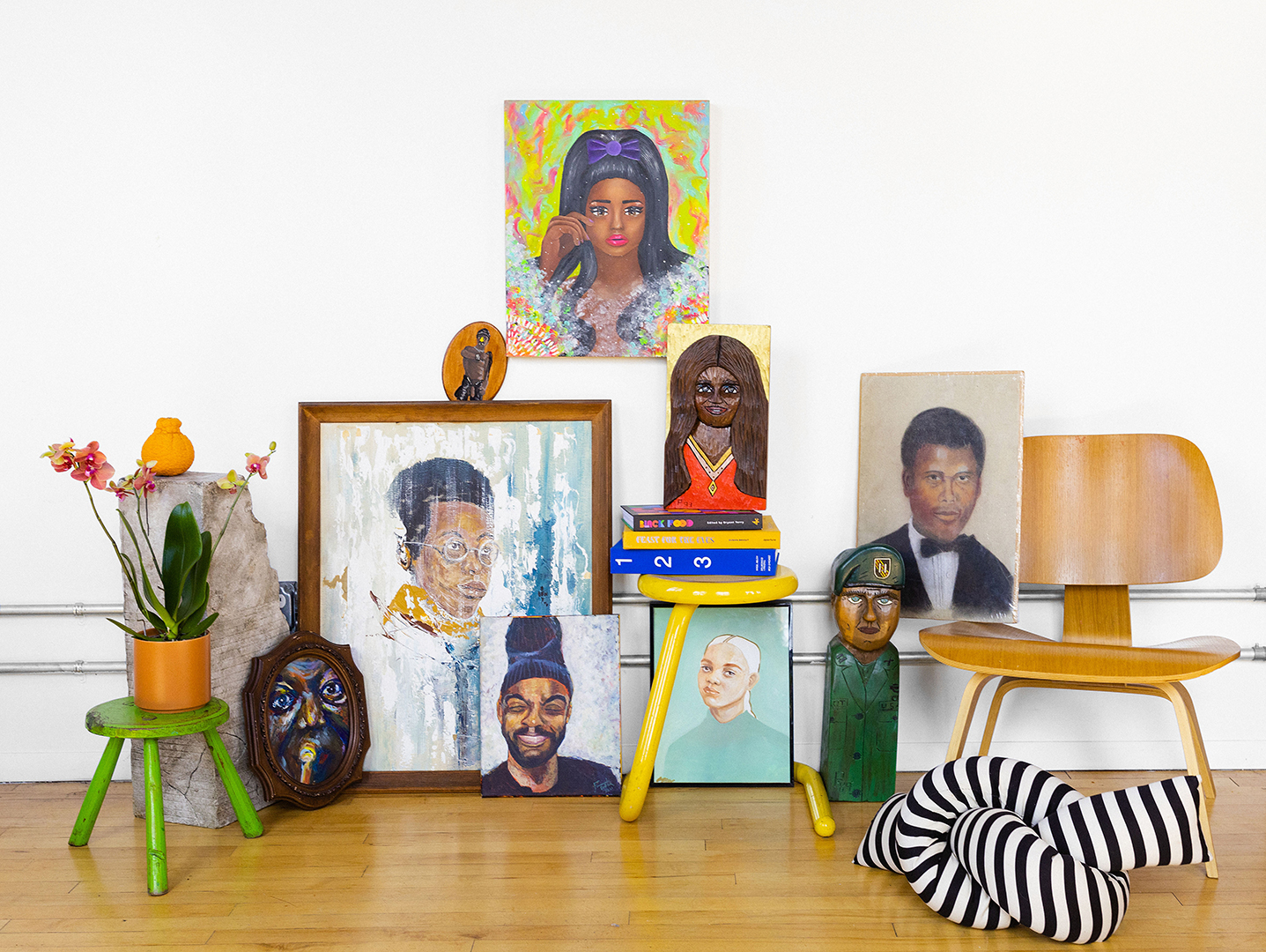 Portraits and a chair and pillow against a wall