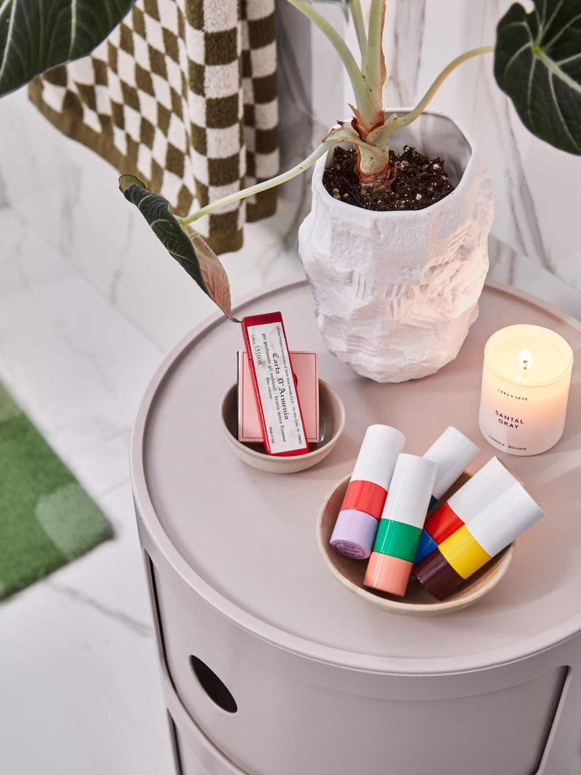 lipsticks, candle, and plant on top of storage unit