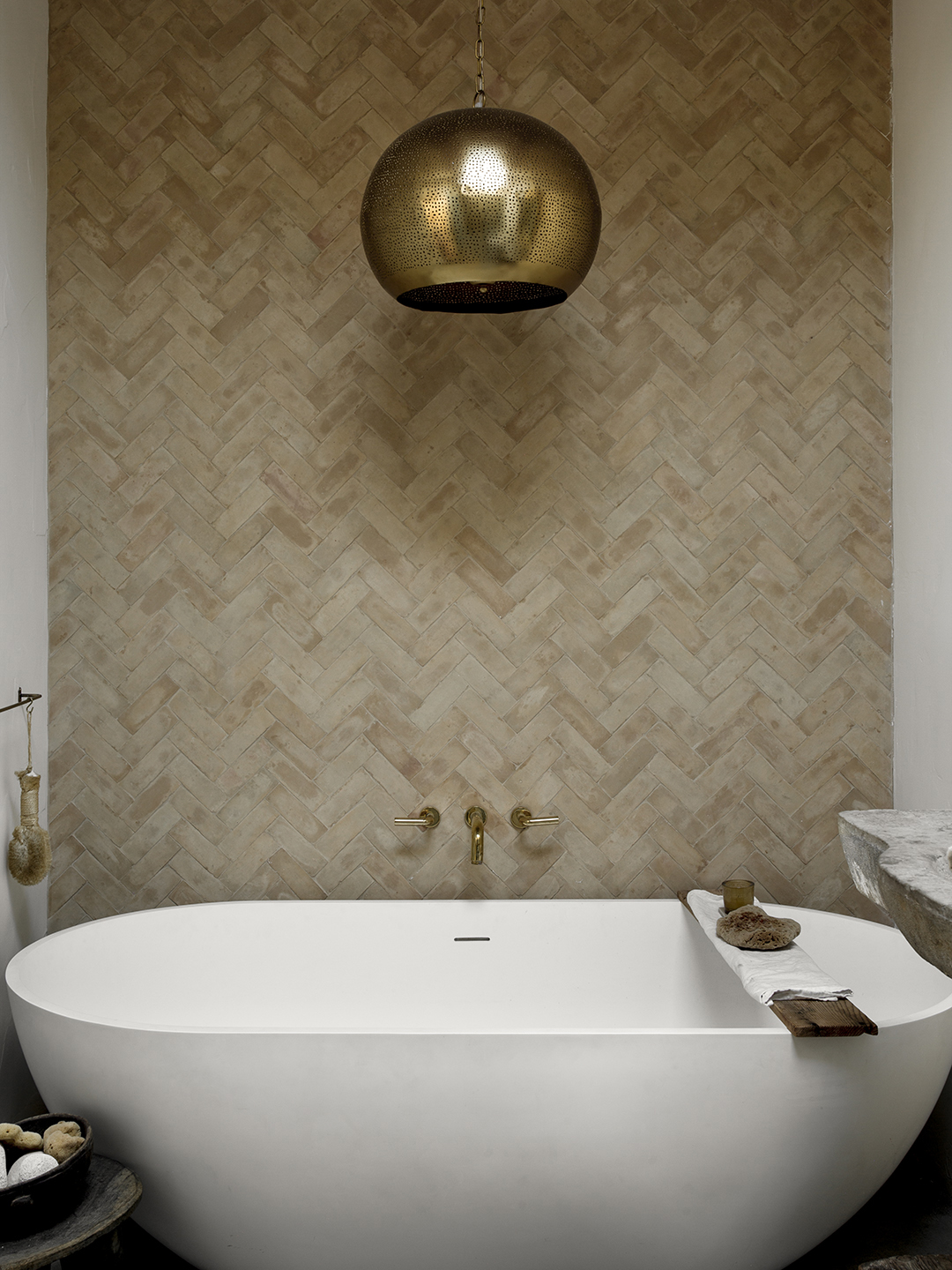 white standing tub in neutral herringbone-tiled nook