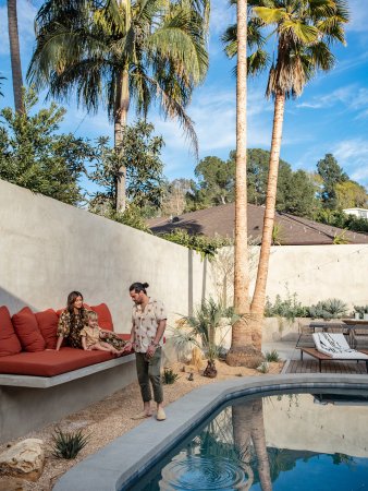 Couple standing by pool in their backyard