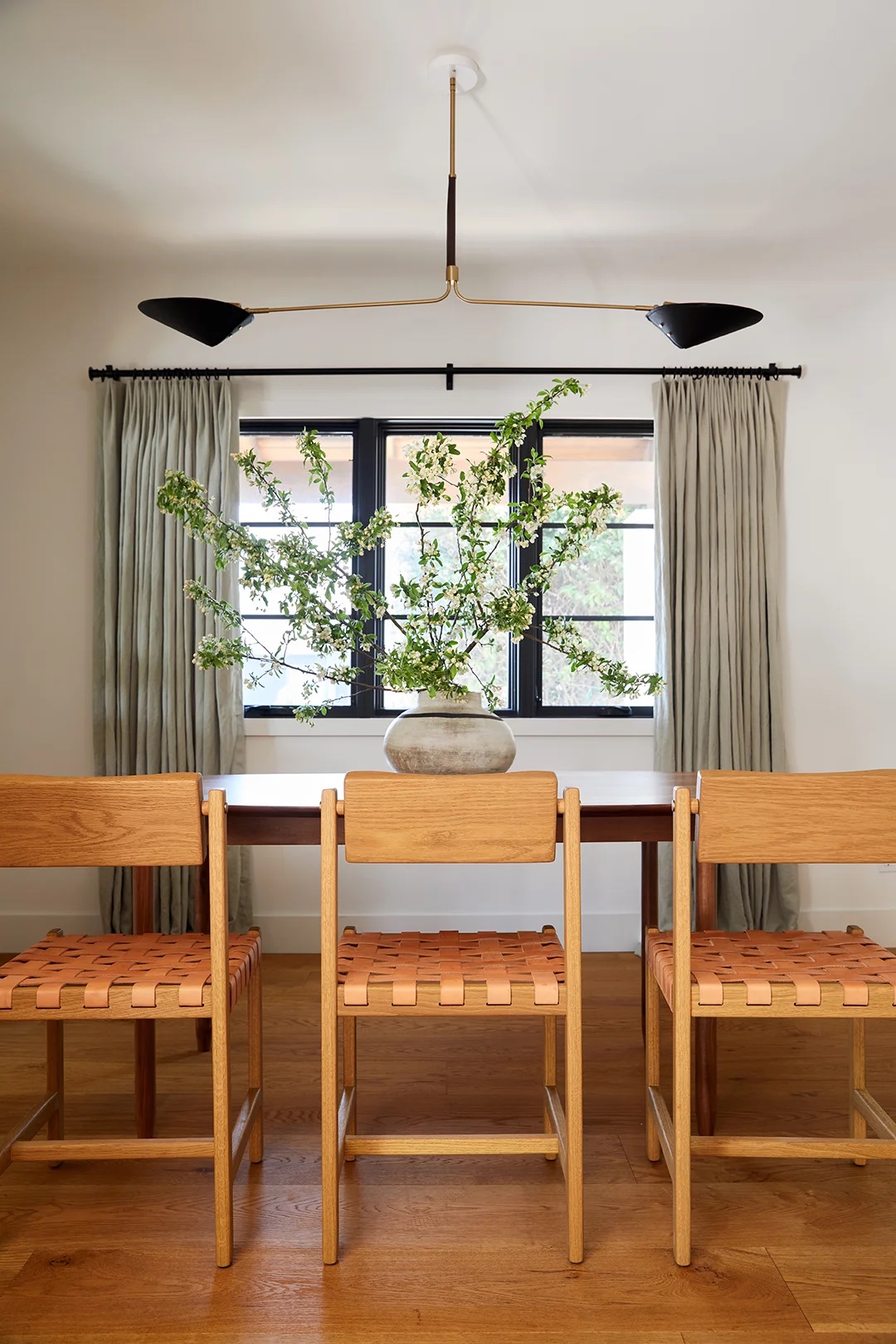 wood and leather dining chairs around dining table under black lighting fixture