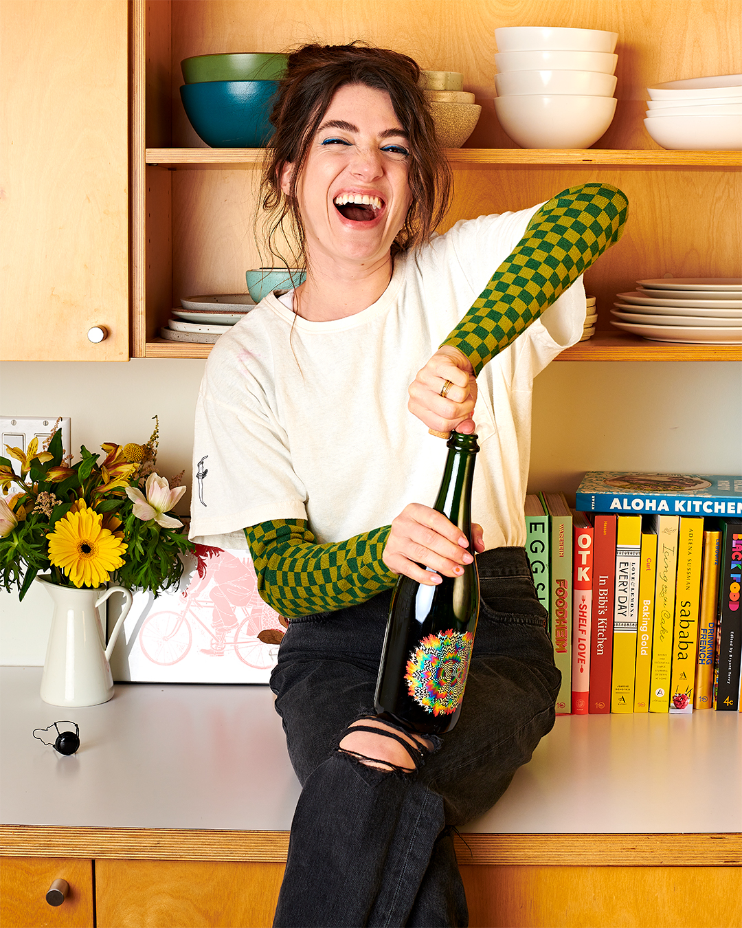 woman sitting on counter opening a bottle of wine