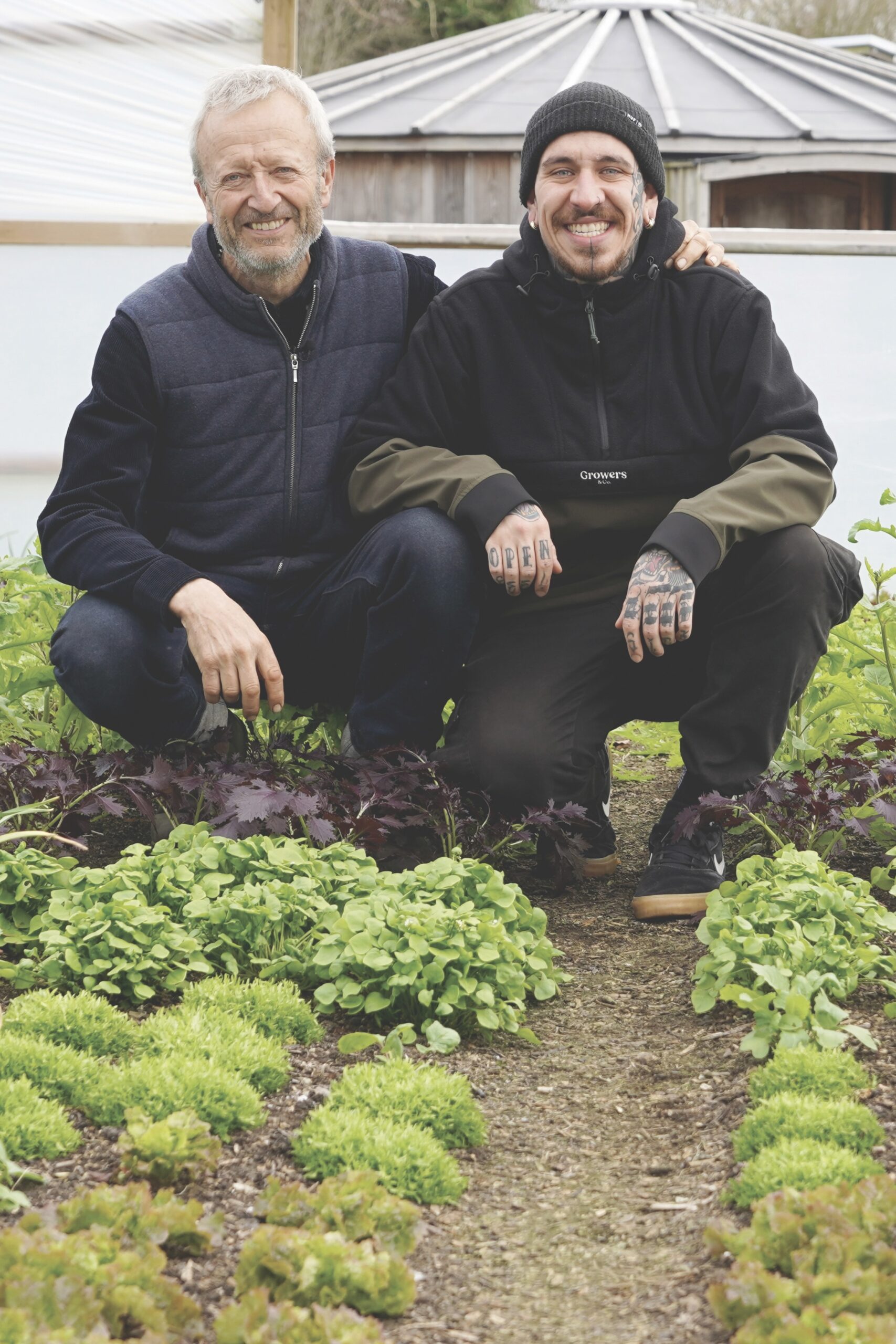 Charles Dowding and Alessandro Vitale crouching in garden