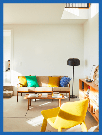 Living room with yellow chair and midcentury-style sofa.