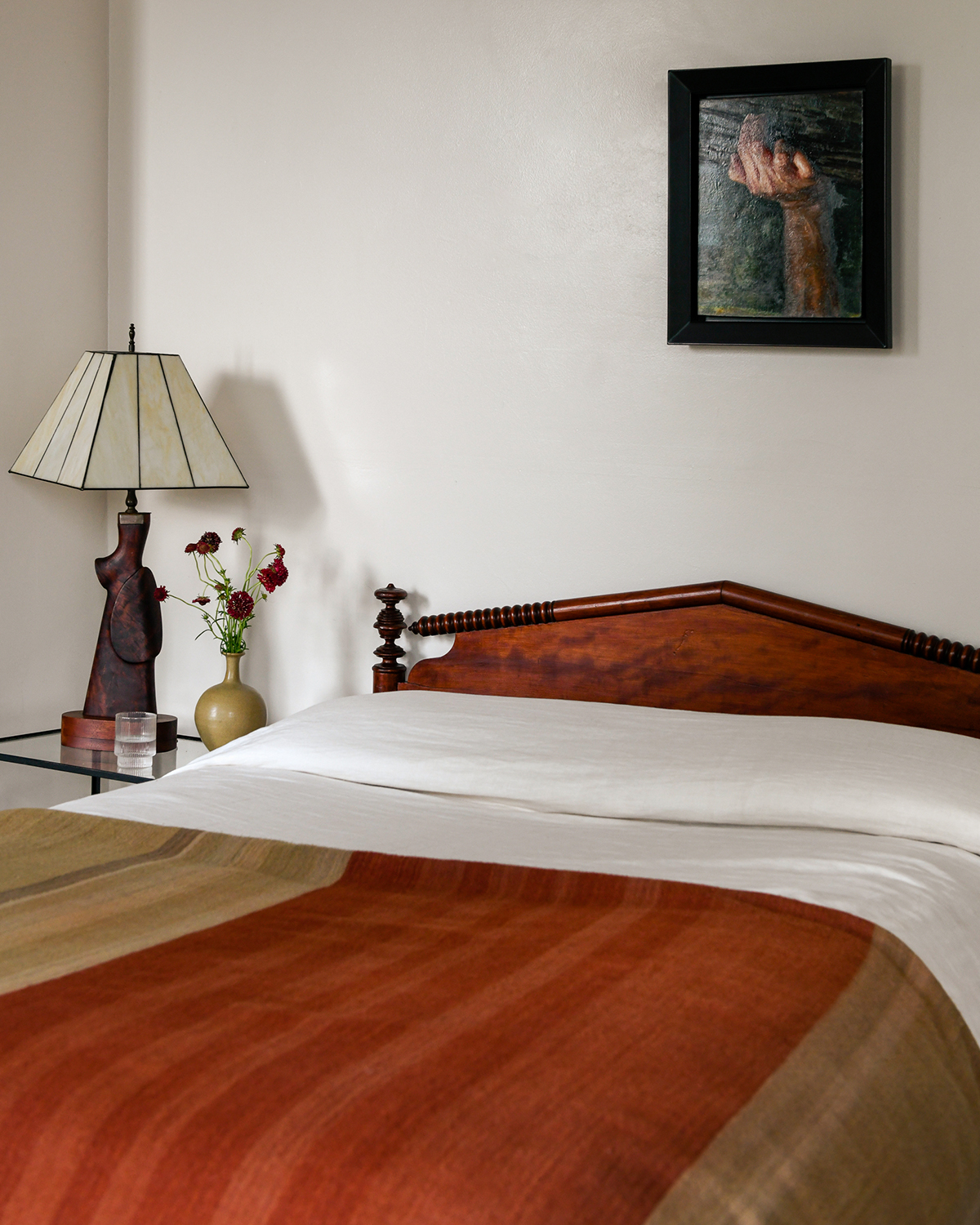 Antique bed with white sheets and a Indian blanket