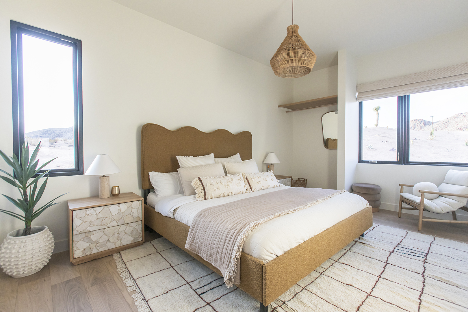 Primary bedroom with curvy tan headboard and a check rug