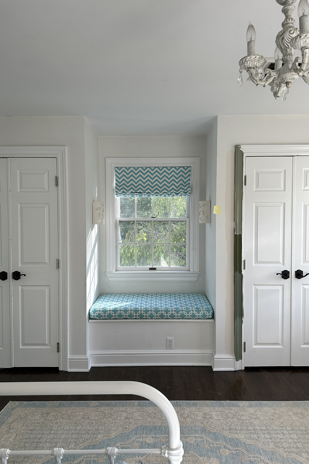 All-white room with two doors bookending a window.