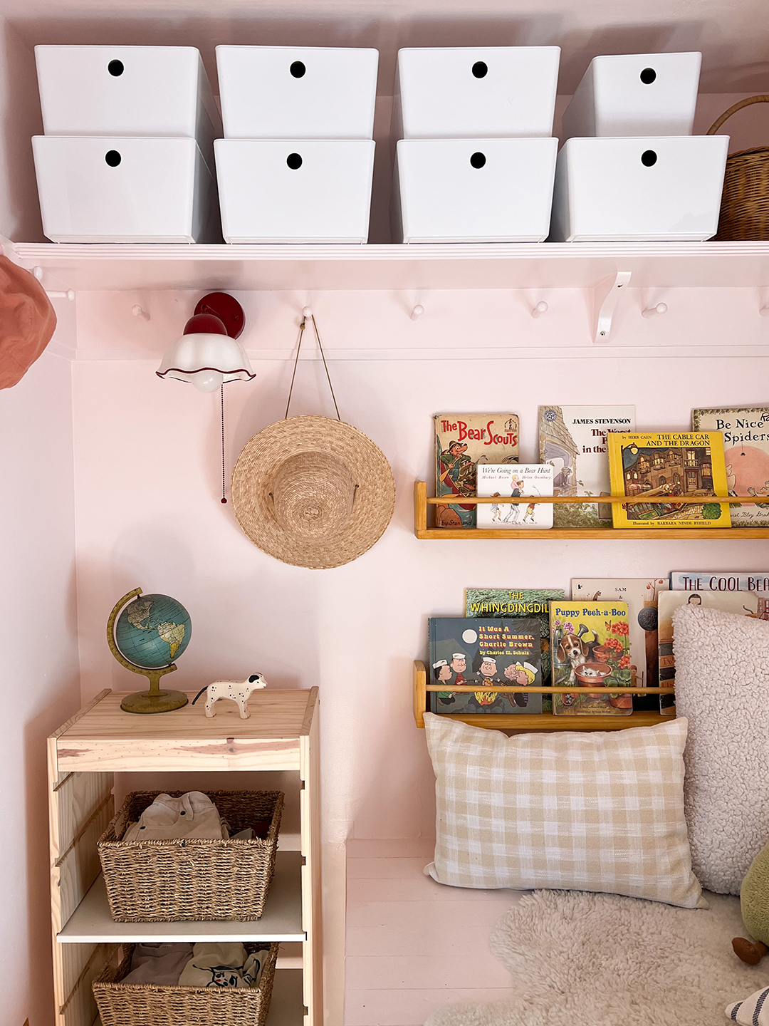 Kid's closet with white storage boxes on a shelf, bookshelves, and pegs. 