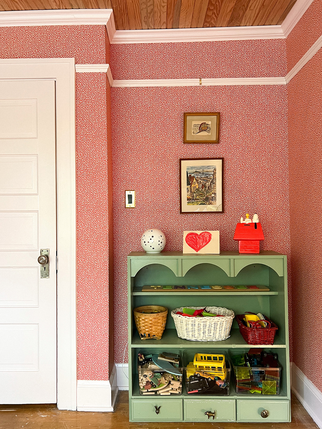 Kid's room with green scalloped book shelves and white door.