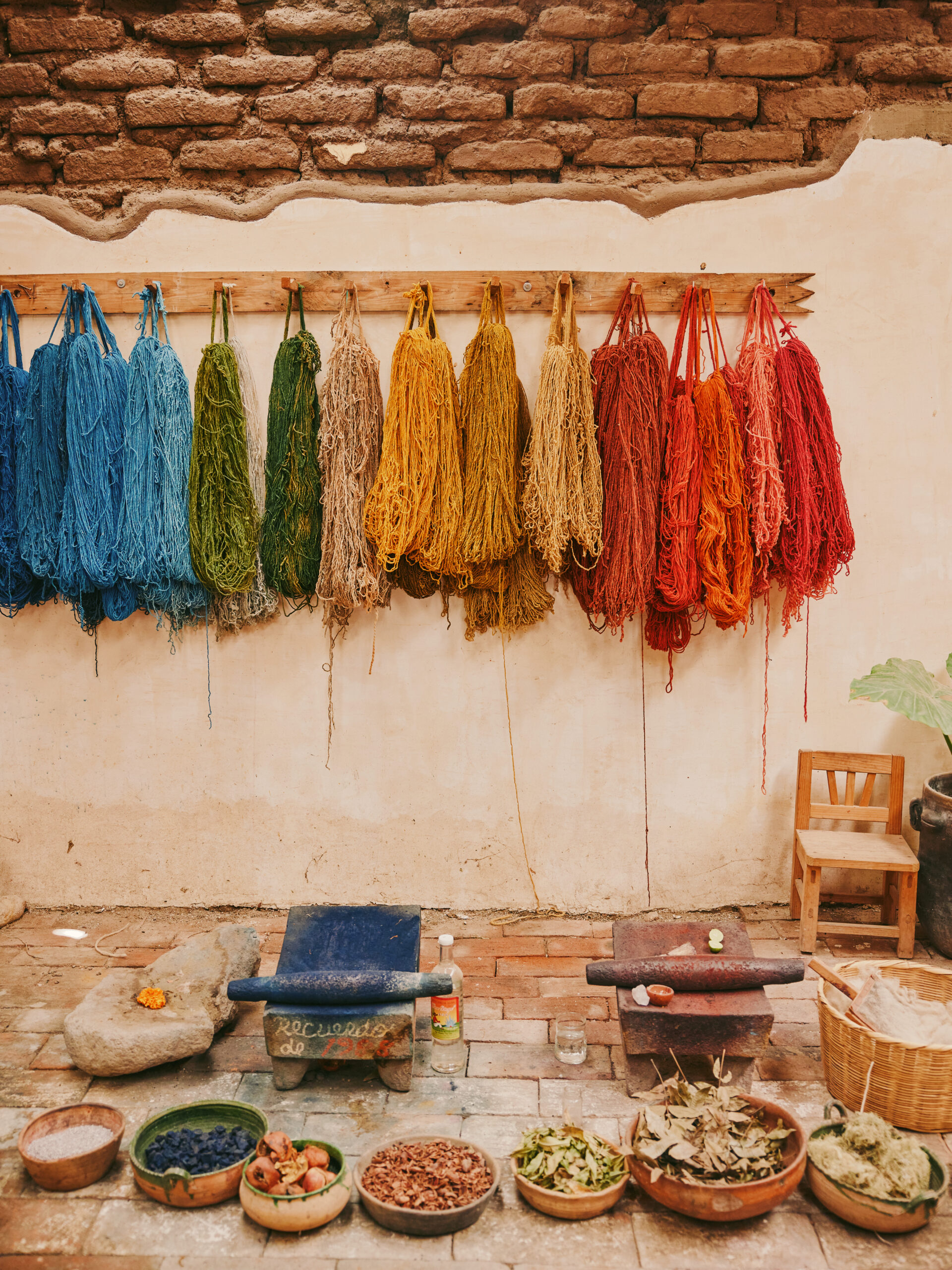 Colorful dyed yarns hanging to dry against plaster wall in Teotitlán del Valle, Mexico.