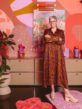 Woman in a leopard dress standing in front of a pink and orange mural