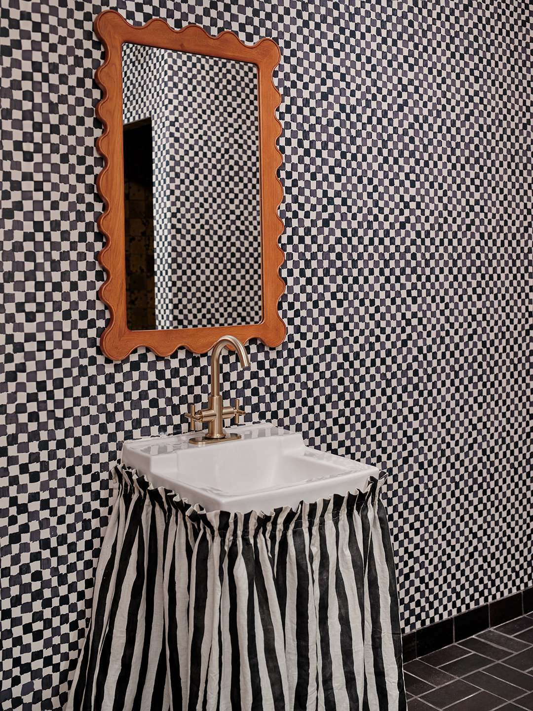 Checkerboard wallpaper and striped skirt around sink