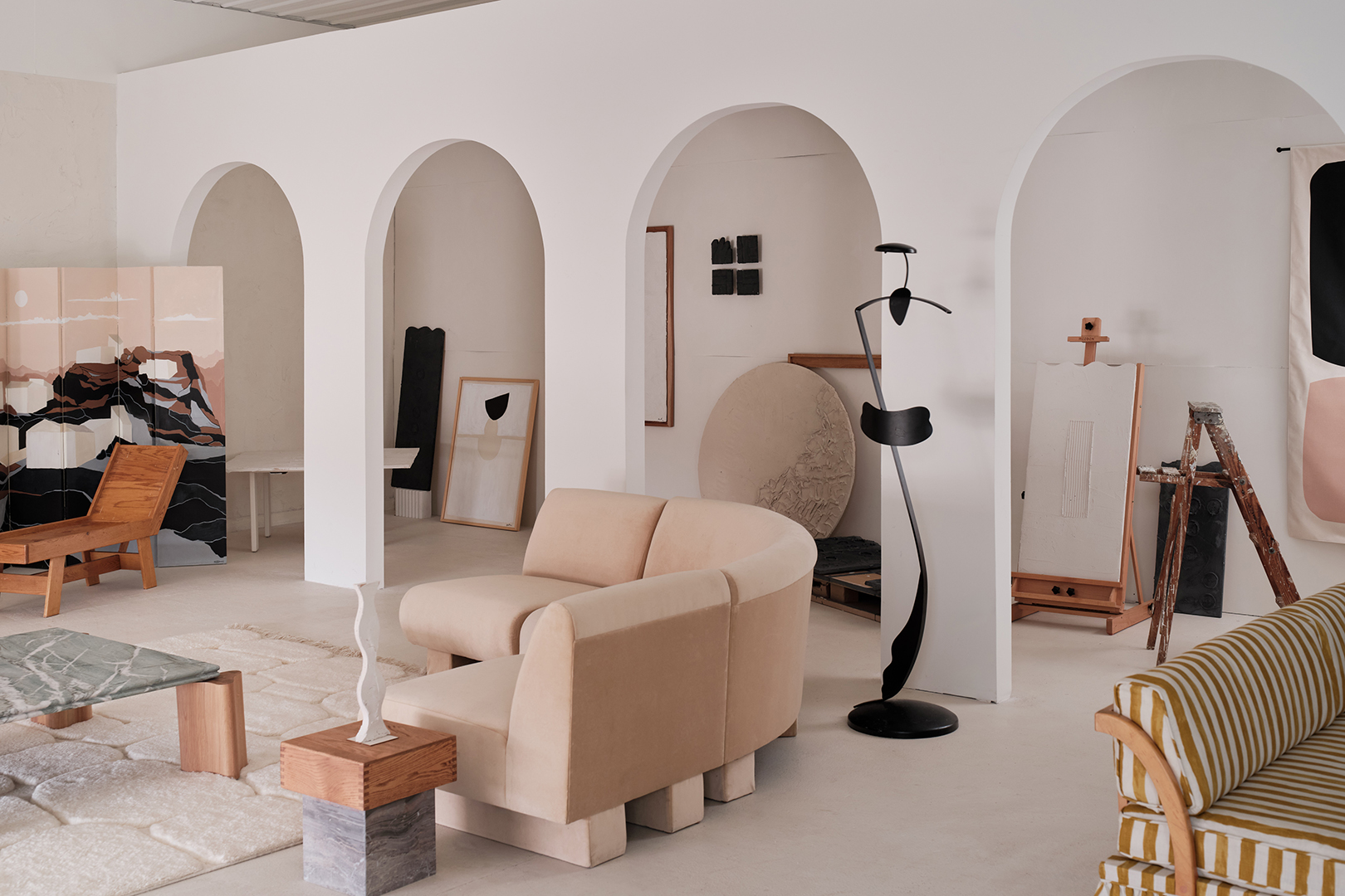 Arches in wall that make a hallway; curved sofa in foreground