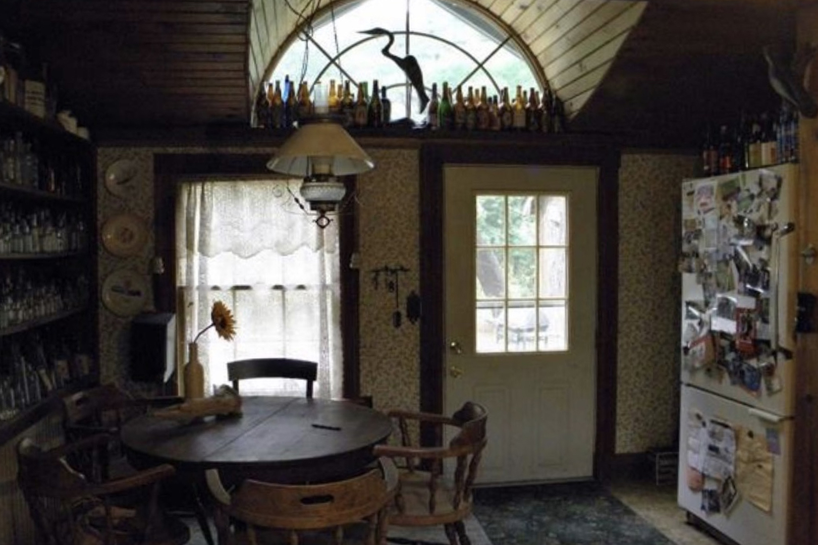 Kitchen entryway with bottles lined up on a shelf above the door