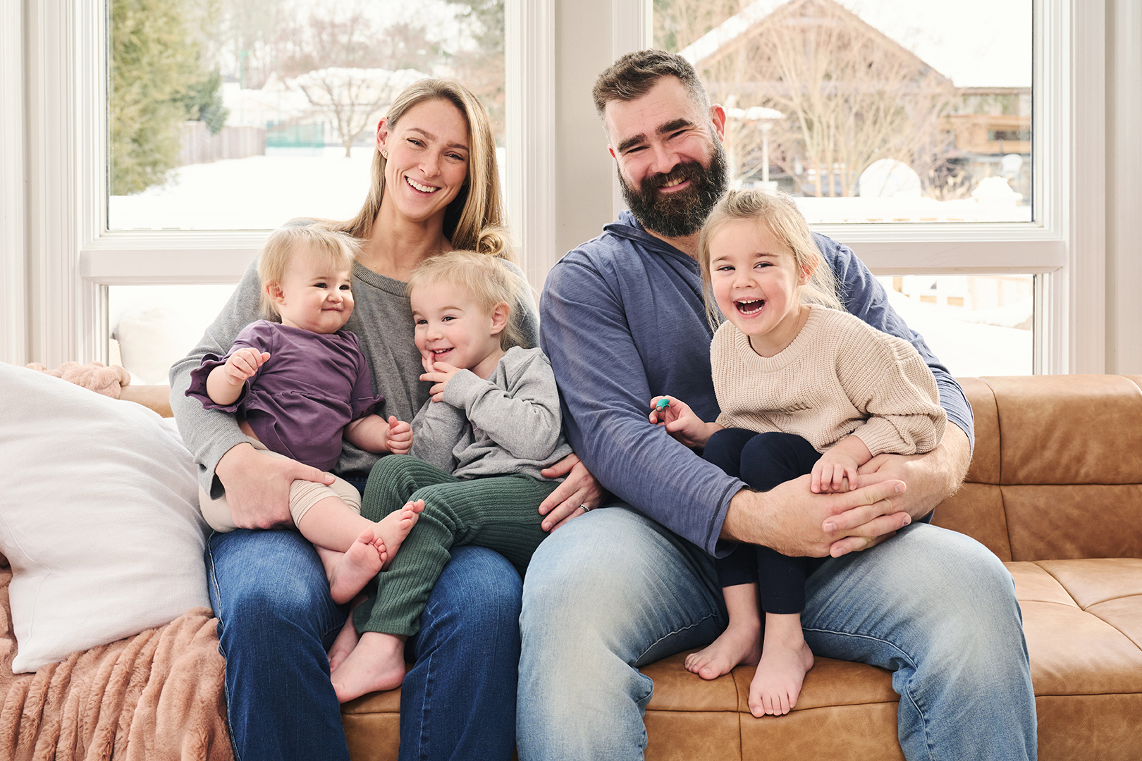 Family of mom, dad, and three girls posing on a sofa