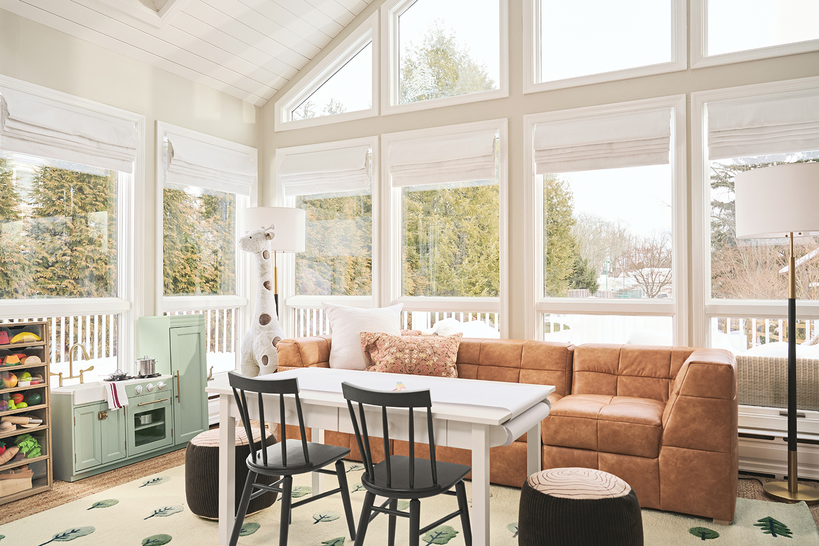 Entire playroom with windows and black chairs, white table, and leather sofa