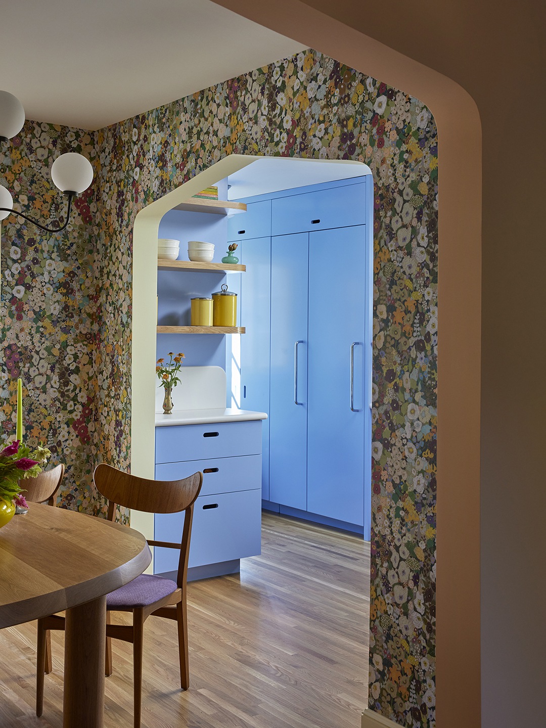 View of kitchen from floral wallpapered dining room