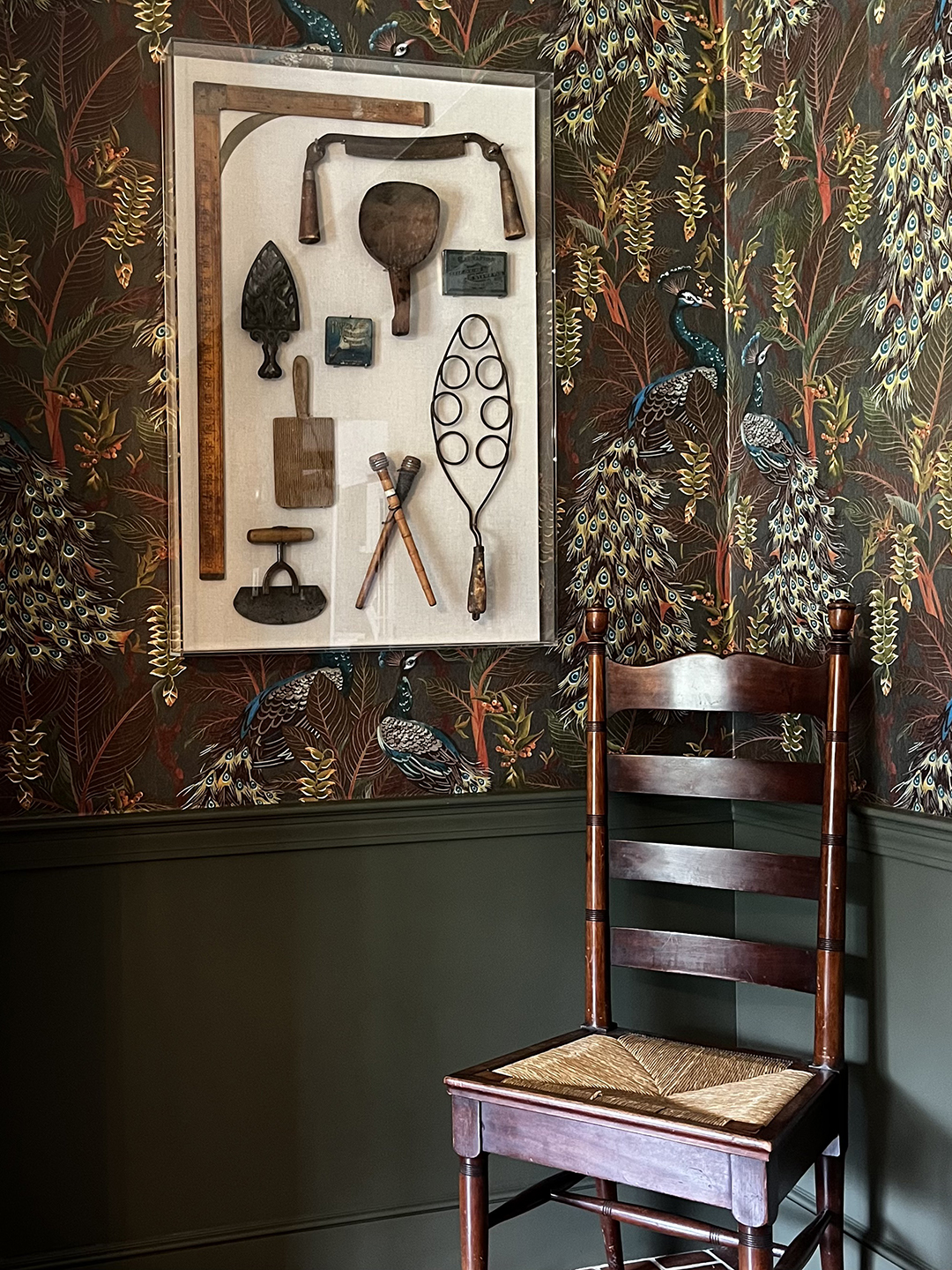 Old artifacts in a shadowbox hanging on a wall covered in wallpaper