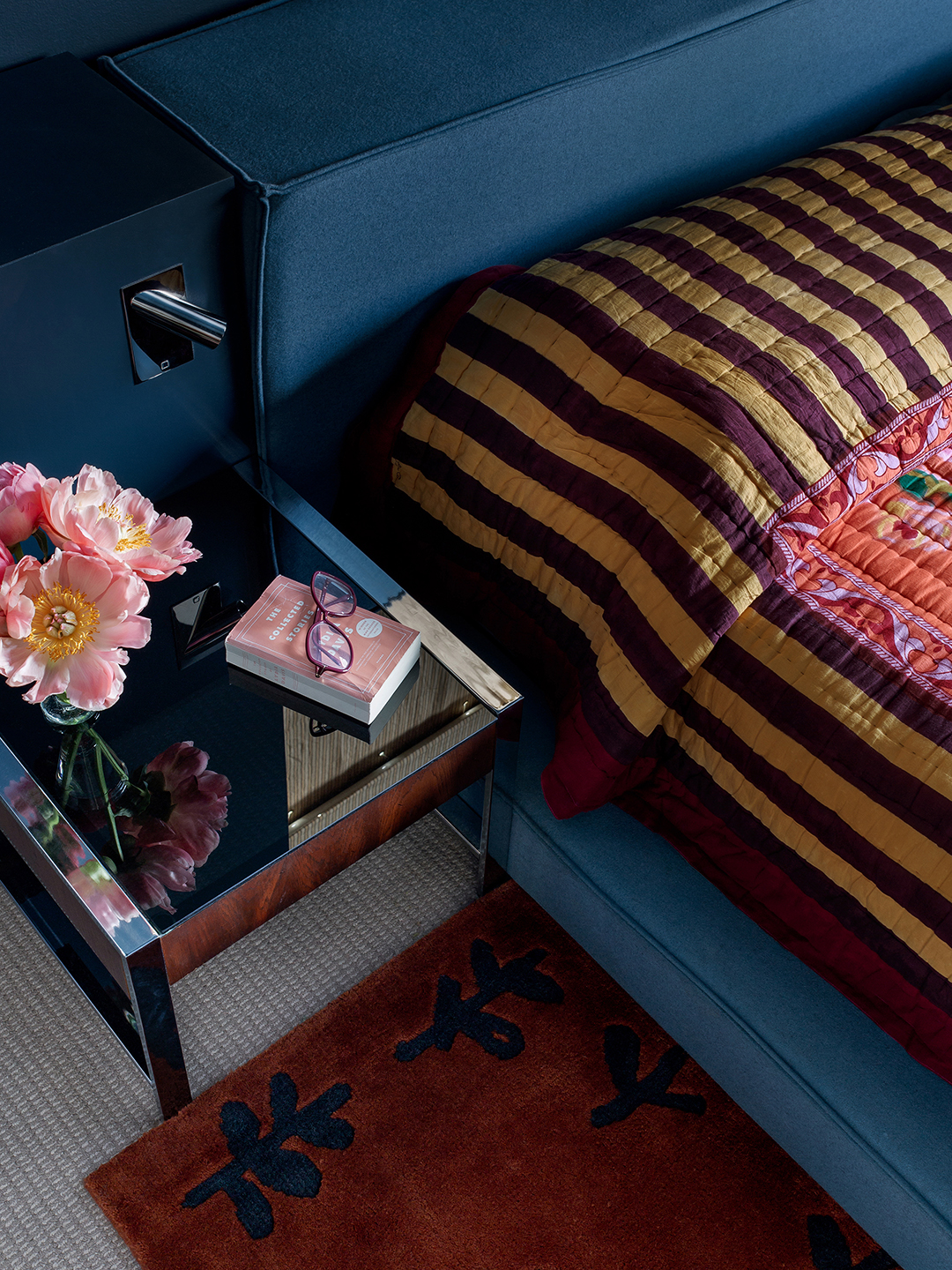 striped bedding against a dark blue upholstered headboard