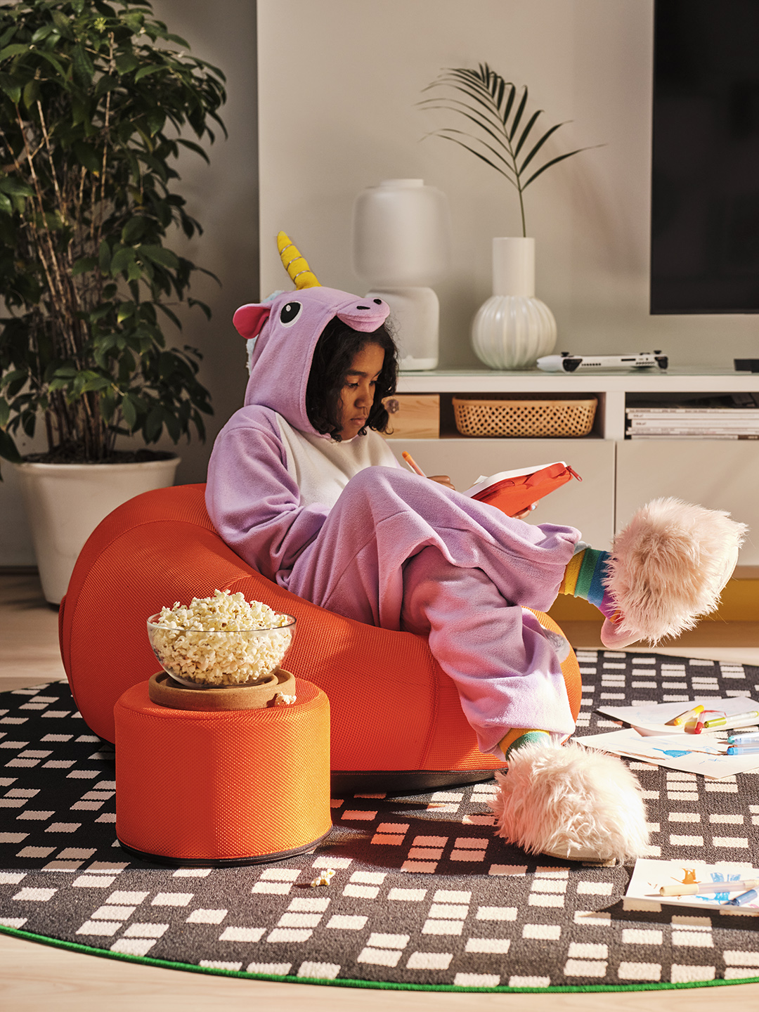 Girl in unicorn onesie playing video games on an orange inflatable chair