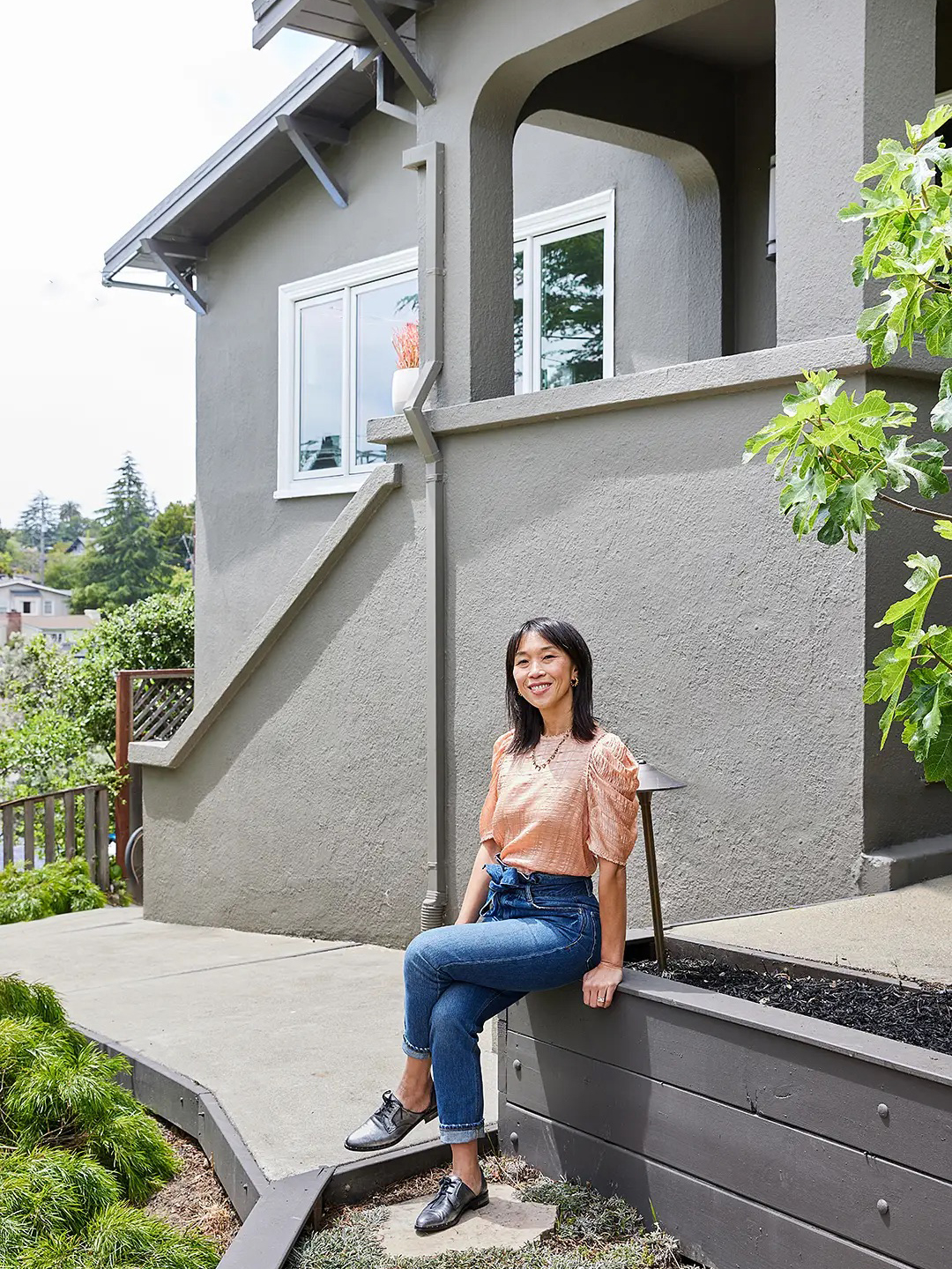 woman outside of gray house