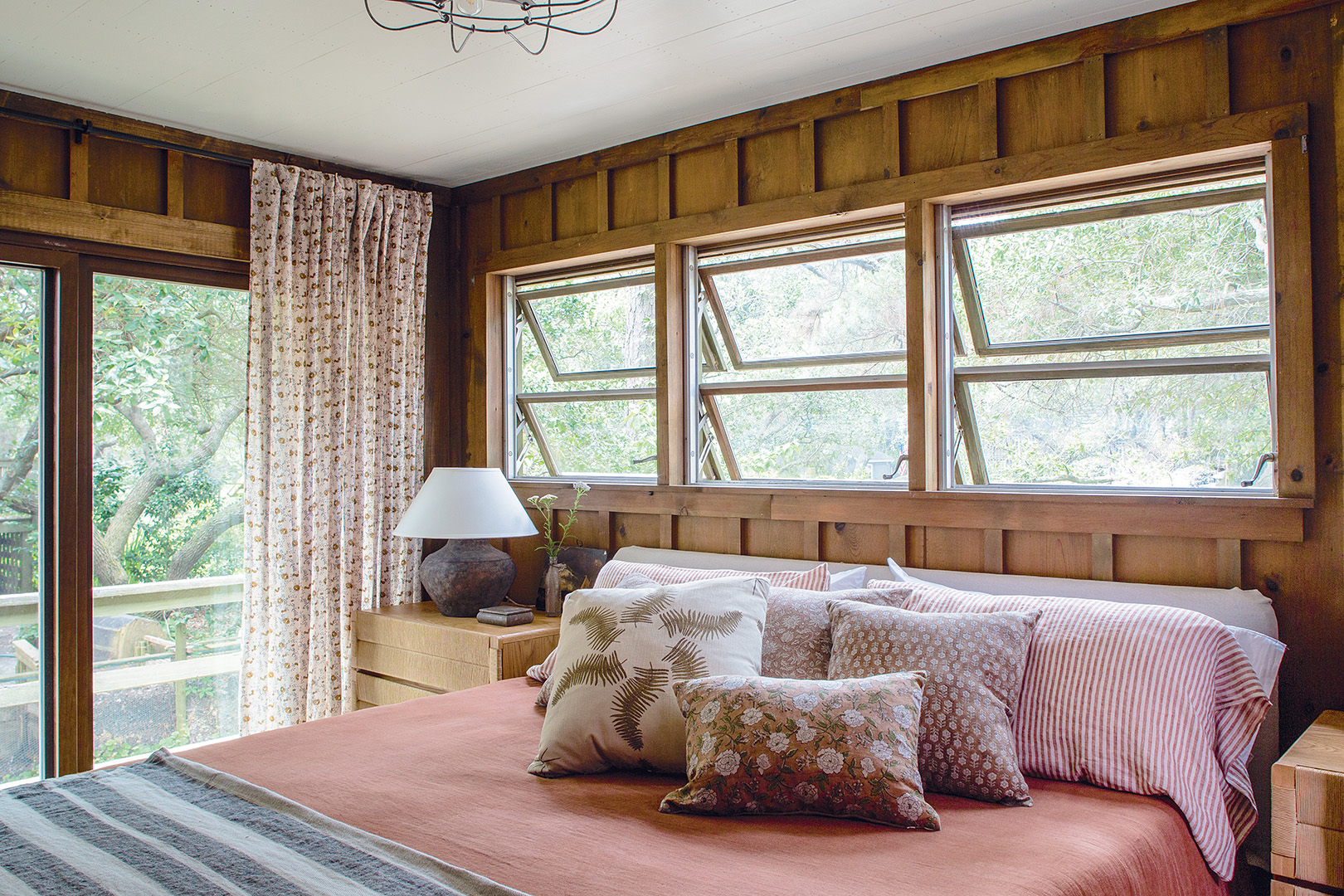 Bedroom with pink sheets and windows above bed