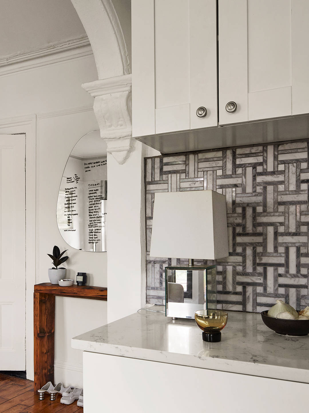 Tile backsplash with white cabinets and art deco lamp