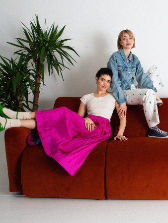 Two people sitting on a burnt red sofa